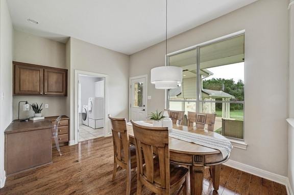 dining area featuring baseboards, washer and clothes dryer, and wood finished floors