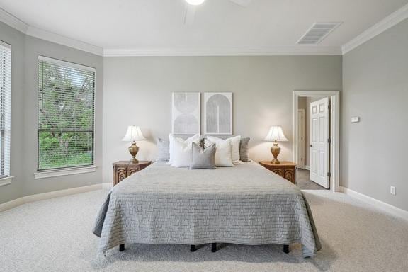 carpeted bedroom with visible vents, ornamental molding, and multiple windows