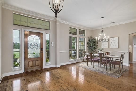 foyer with a healthy amount of sunlight, baseboards, wood-type flooring, and a notable chandelier
