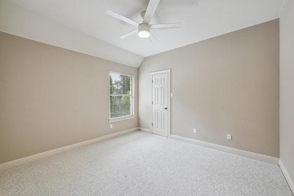 empty room with vaulted ceiling, baseboards, light carpet, and a ceiling fan