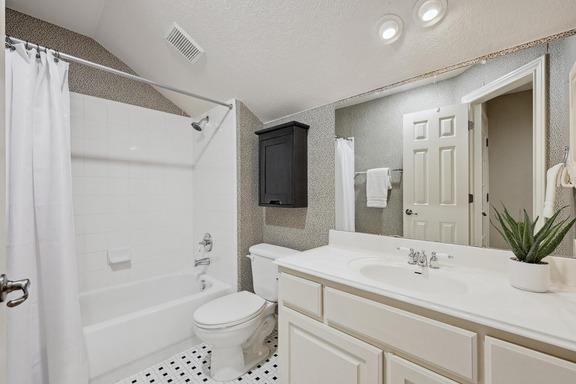 full bathroom featuring visible vents, vanity, lofted ceiling, toilet, and shower / bath combo