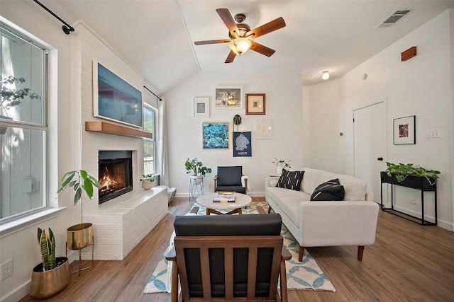living area featuring a ceiling fan, visible vents, wood finished floors, and a fireplace