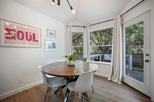 dining area featuring baseboards, wood finished floors, and vaulted ceiling