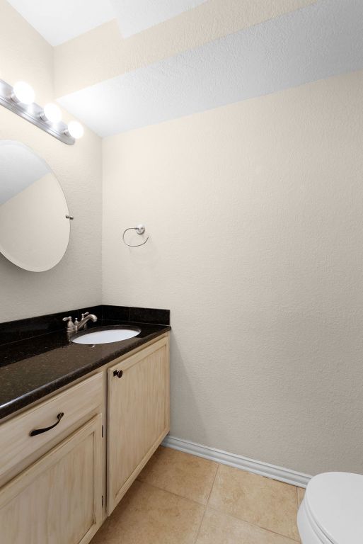 1809 Woodland Dr, Cedar Park, TX 78613 - half bath featuring vanity, baseboards, tile patterned floors, and toilet