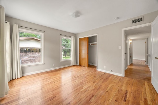 unfurnished bedroom featuring baseboards, visible vents, light wood finished floors, and a closet
