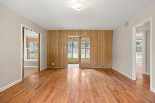 empty room featuring baseboards, a healthy amount of sunlight, and light wood-style flooring