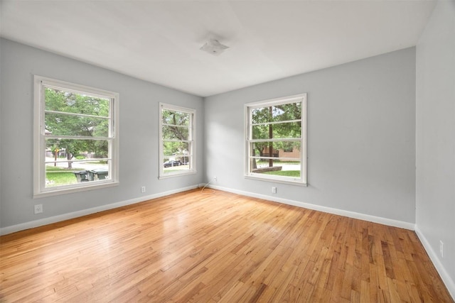 spare room with baseboards and light wood finished floors