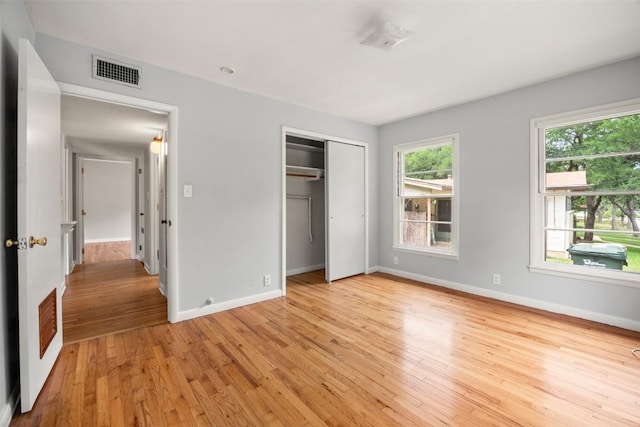 unfurnished bedroom with baseboards, visible vents, light wood-style flooring, and a closet