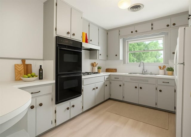 kitchen with gas cooktop, a sink, dobule oven black, freestanding refrigerator, and visible vents