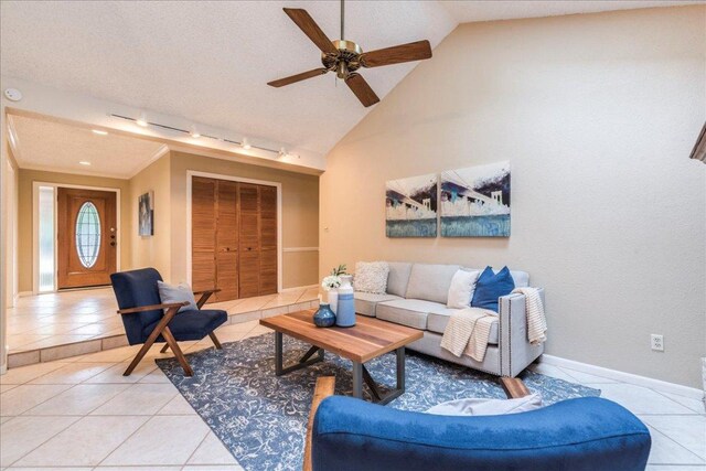 living area with light tile patterned flooring, rail lighting, a ceiling fan, baseboards, and lofted ceiling