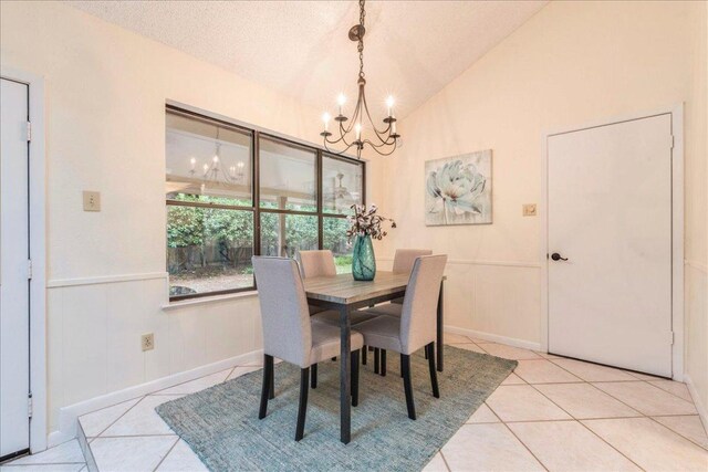 dining area with baseboards, an inviting chandelier, light tile patterned floors, and lofted ceiling