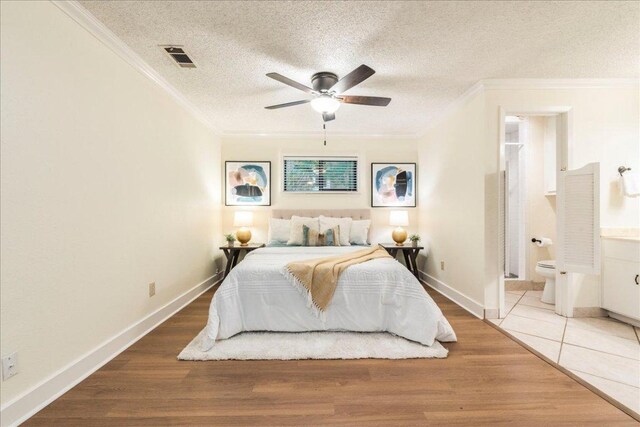 bedroom with crown molding, visible vents, wood finished floors, baseboards, and a textured ceiling