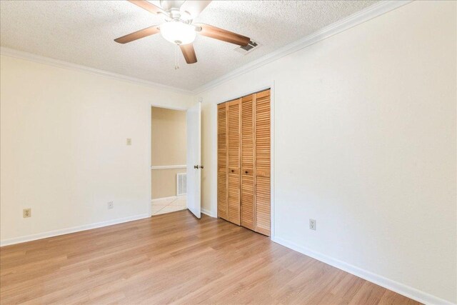 unfurnished bedroom with visible vents, a textured ceiling, light wood-style floors, and a closet