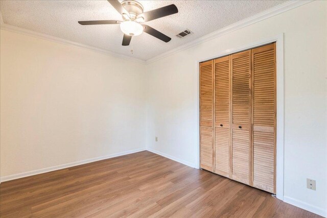 unfurnished bedroom with visible vents, a closet, wood finished floors, baseboards, and a textured ceiling