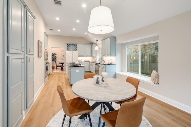 dining room featuring baseboards, visible vents, lofted ceiling, and light wood finished floors