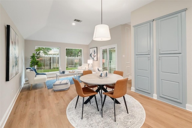 dining area featuring visible vents, baseboards, light wood finished floors, and lofted ceiling