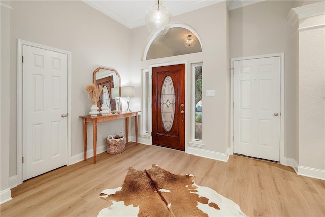 foyer entrance with baseboards, ornamental molding, and wood finished floors