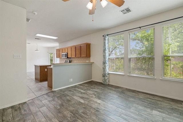 kitchen featuring visible vents, a ceiling fan, plenty of natural light, and stainless steel microwave