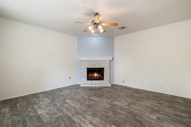 unfurnished living room featuring visible vents, baseboards, a stone fireplace, ceiling fan, and dark wood-style floors