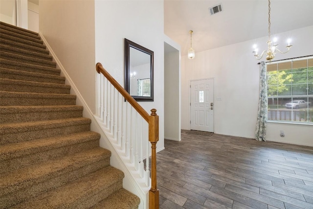 foyer featuring visible vents, wood finished floors, stairway, baseboards, and a notable chandelier