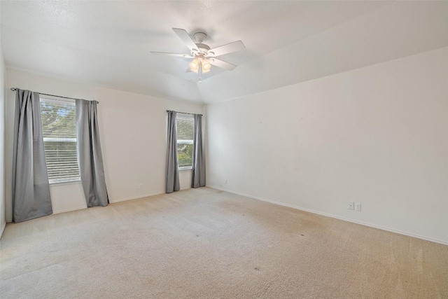 spare room featuring baseboards, a ceiling fan, and light carpet