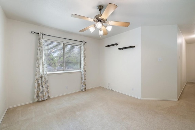 carpeted empty room featuring baseboards and ceiling fan