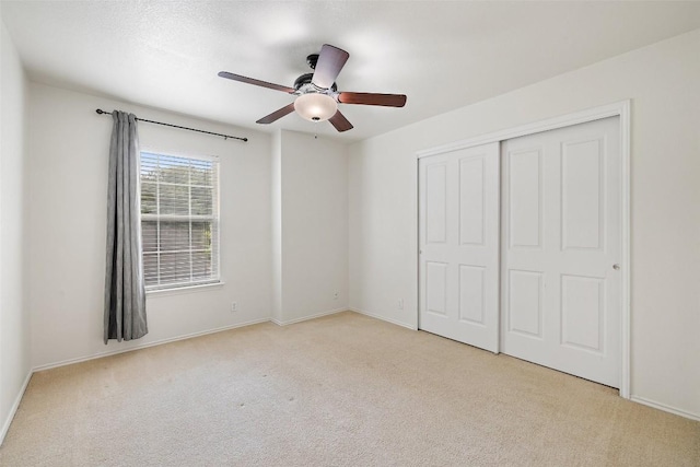 unfurnished bedroom featuring carpet floors, baseboards, ceiling fan, and a closet