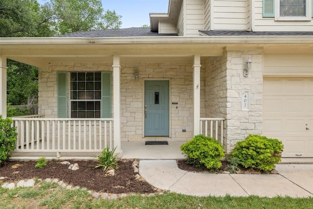 property entrance featuring covered porch, roof with shingles, and stone siding