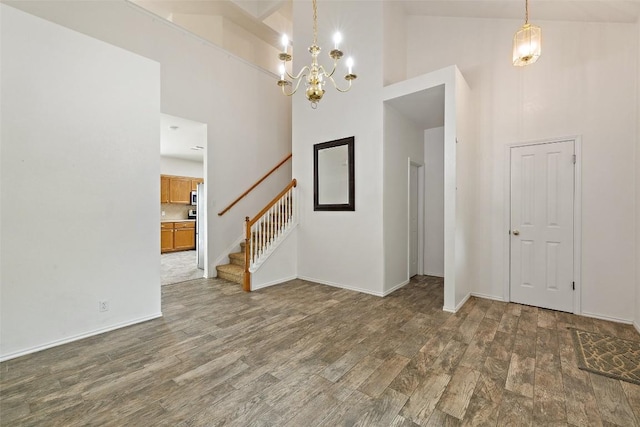 interior space with an inviting chandelier, high vaulted ceiling, baseboards, wood finished floors, and stairway