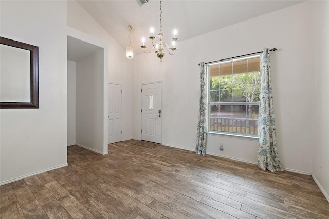 empty room featuring visible vents, wood finished floors, high vaulted ceiling, baseboards, and a notable chandelier