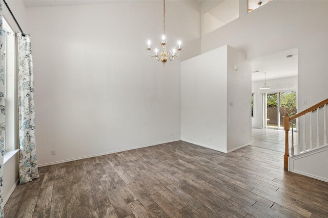 unfurnished room with baseboards, stairs, wood finished floors, and a chandelier
