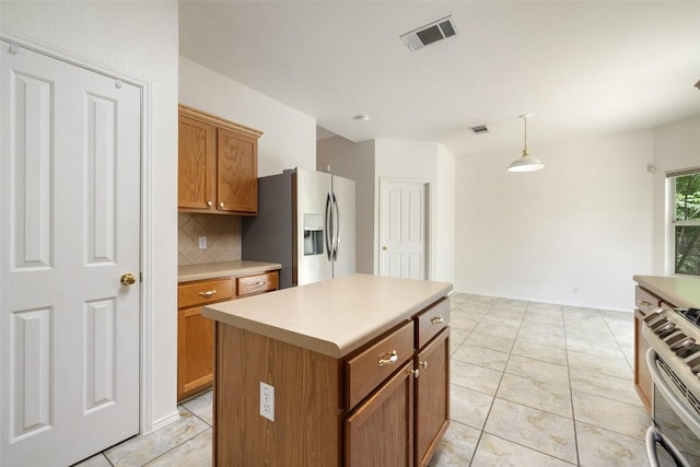 407 N Lori Cir, Bastrop, TX 78602 - kitchen with stainless steel appliances, brown cabinets, backsplash, decorative light fixtures, and light countertops