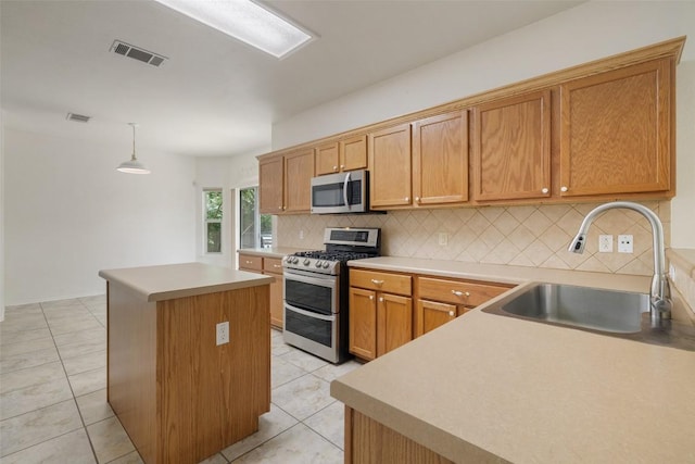 kitchen featuring visible vents, a center island, a sink, appliances with stainless steel finishes, and backsplash