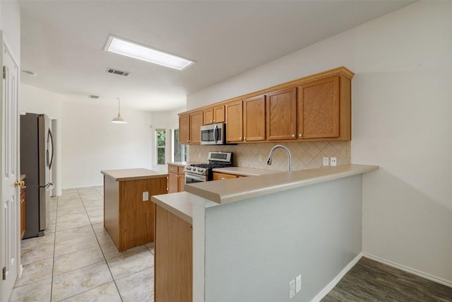 407 N Lori Cir, Bastrop, TX 78602 - kitchen featuring stainless steel appliances, a kitchen island, decorative backsplash, light countertops, and a peninsula