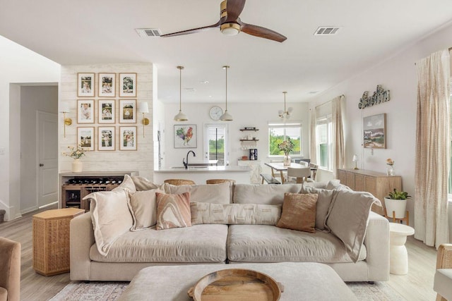 living area featuring a ceiling fan, light wood finished floors, and visible vents