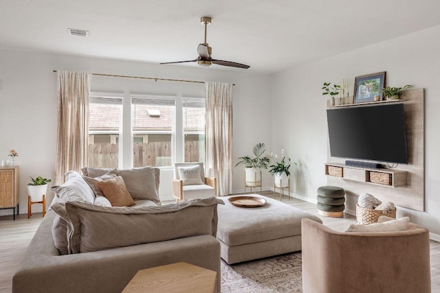 living area featuring baseboards, ceiling fan, light wood-style flooring, and visible vents