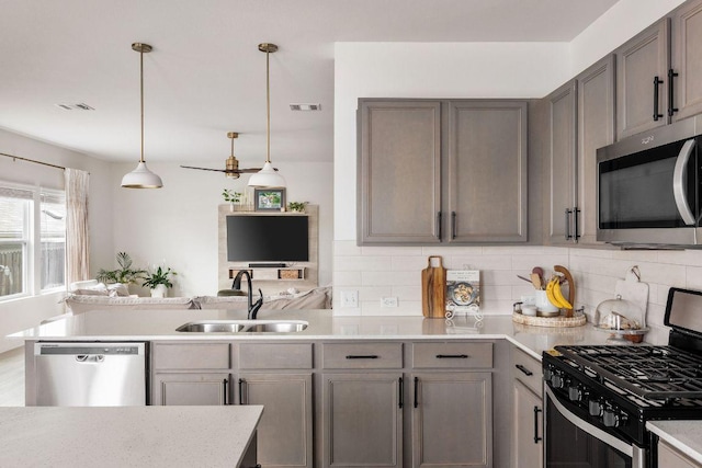 kitchen featuring appliances with stainless steel finishes, a sink, light countertops, decorative backsplash, and visible vents