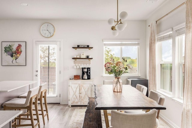 dining area featuring an inviting chandelier, baseboards, and light wood-style flooring