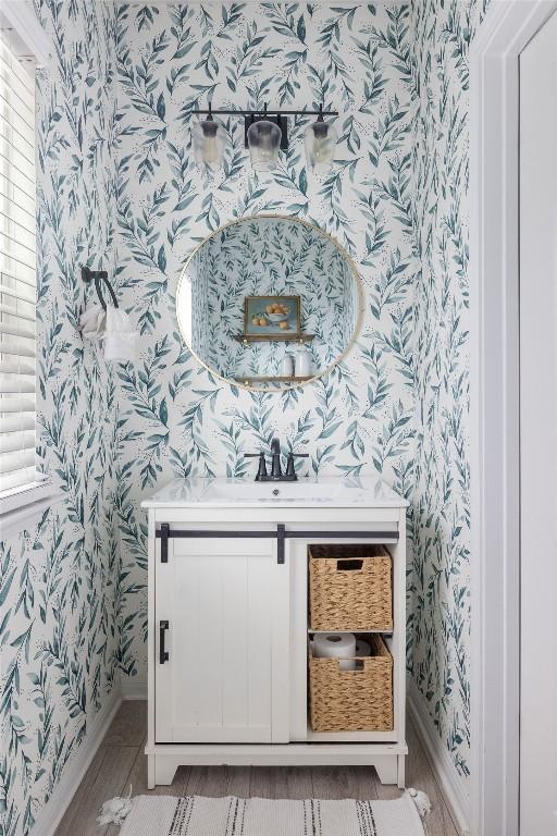 interior space featuring baseboards, a sink, and wallpapered walls