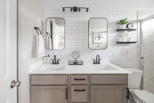 bathroom with double vanity, toilet, decorative backsplash, and a sink