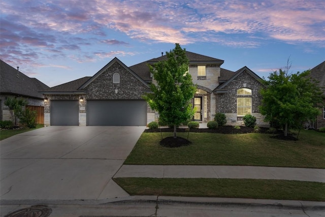 view of front of home with an attached garage, concrete driveway, a front lawn, and stone siding