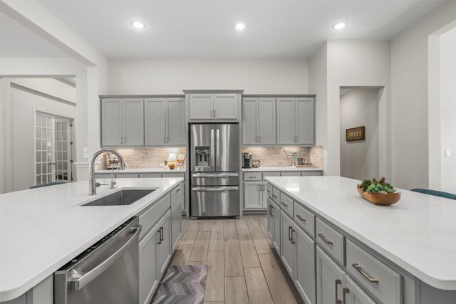 kitchen with a sink, a large island, gray cabinets, and stainless steel appliances