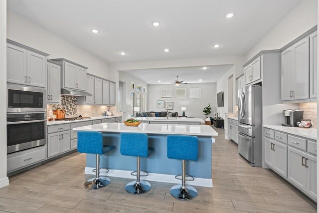 kitchen featuring gray cabinets, a kitchen island, stainless steel appliances, and light wood-type flooring
