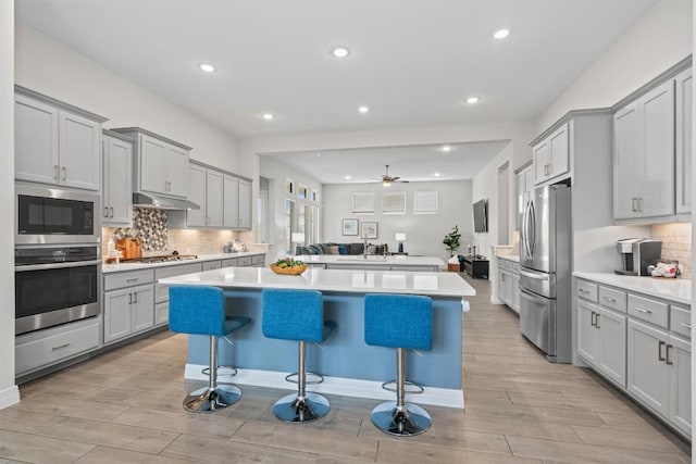 2217 Belen Dr, Leander, TX 78641 - kitchen featuring stainless steel appliances, a center island, light wood-style floors, gray cabinetry, and recessed lighting