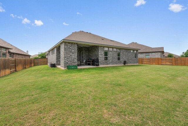 rear view of property with a fenced backyard, a yard, cooling unit, and brick siding