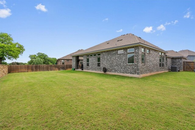 rear view of house featuring a fenced backyard, a yard, and brick siding