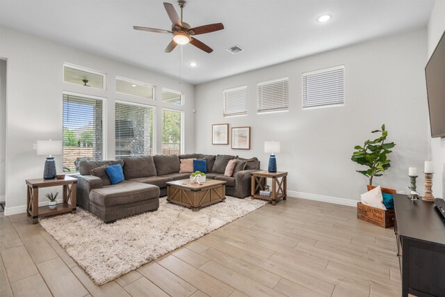 living room with baseboards, ceiling fan, light wood-style flooring, and visible vents
