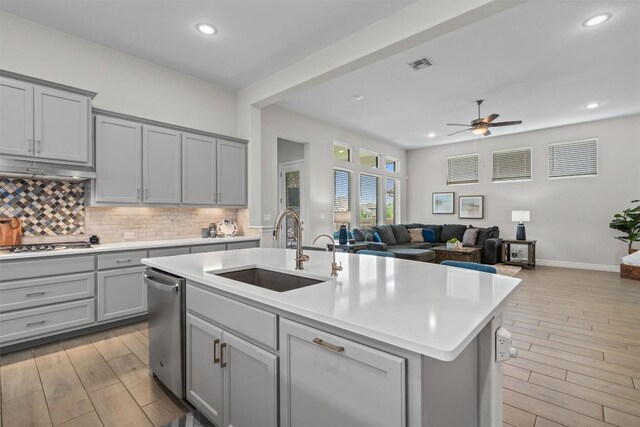 kitchen with ceiling fan, backsplash, a sink, gray cabinetry, and light wood-style flooring