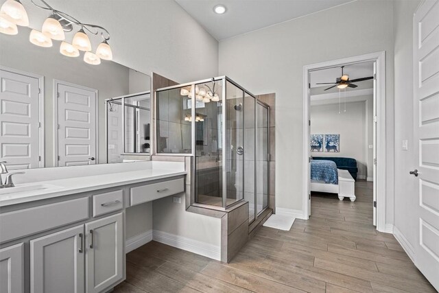 ensuite bathroom featuring baseboards, a shower stall, wood finished floors, and vanity