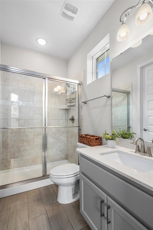2217 Belen Dr, Leander, TX 78641 - full bathroom featuring toilet, vanity, wood finished floors, and a stall shower